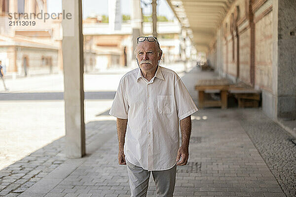 Senior man walking on footpath near building