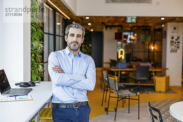 Businessman with arms crossed standing at co working space