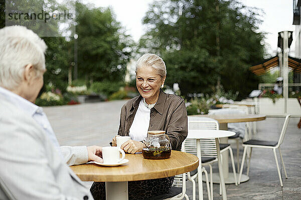 Happy woman with man sitting near table at outdoor cafe