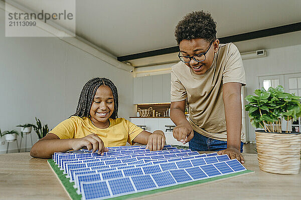 Happy brother and sister preparing solar panels project at home