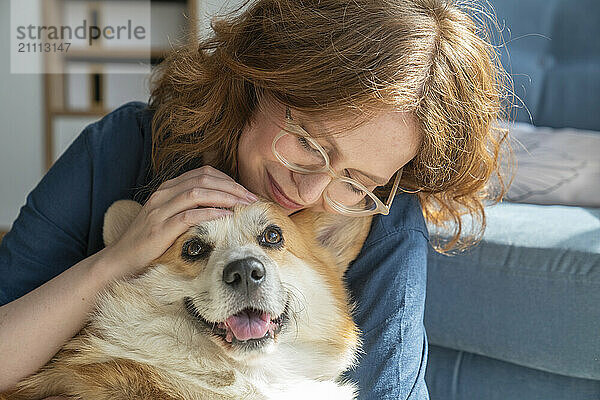 Young woman hugging Welsh Corgi dog at home