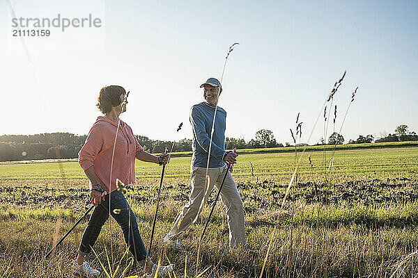 Senior man with woman holding poles and walking on field