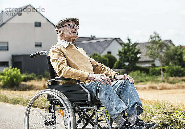 Elderly man sitting in wheelchair in front of houses