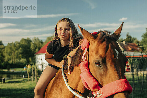 Smiling girl sitting on horse at farm