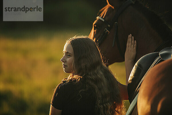 Girl with brown horse in farm