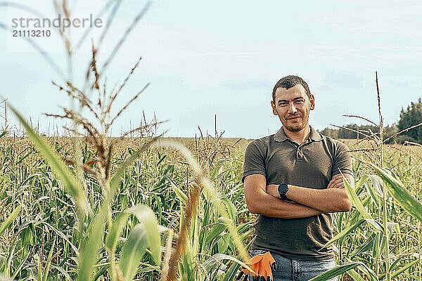 Young man standing with arms crossed in agricultural field