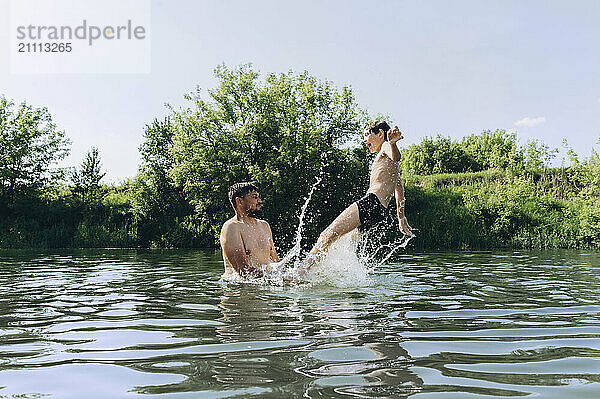 Father playing in water with son at river