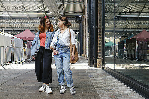 Happy gay couple standing near glass wall in street