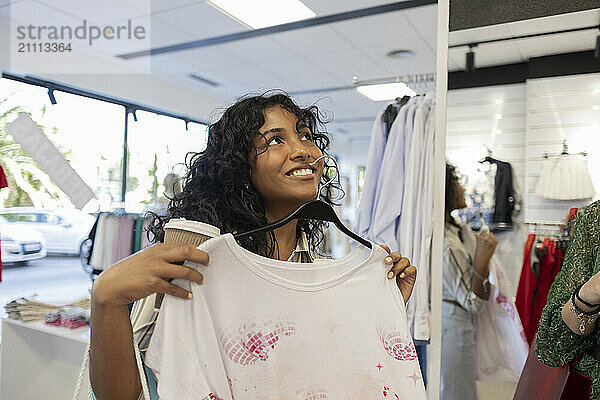 Smiling woman holding new dress at fashion store