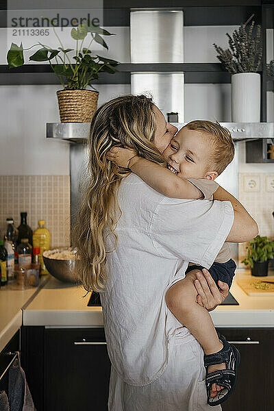 Mother embracing son in kitchen at home