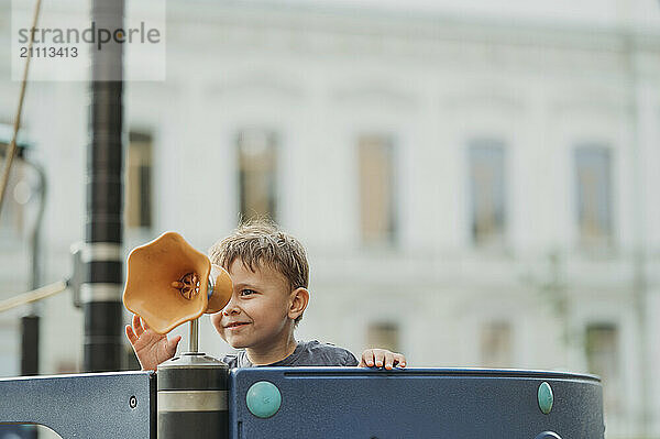 Smiling boy looking through object at playground