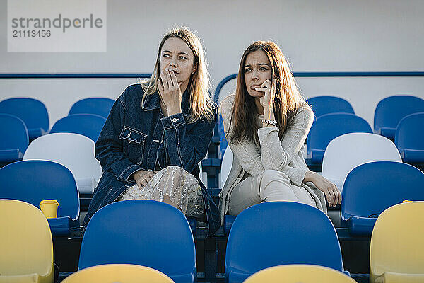 Thoughtful friends watching sport at stadium