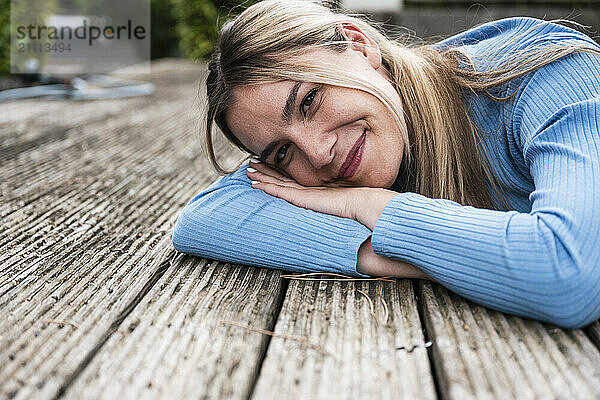 Smiling blond woman lying on wooden patio