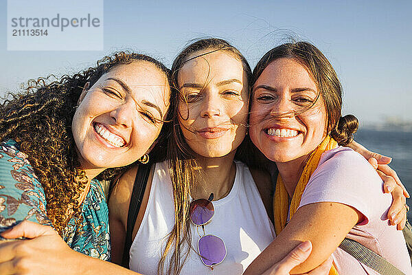 Happy female friends embracing each other on sunny day