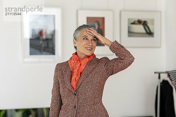 Smiling woman with head in hand standing in art museum