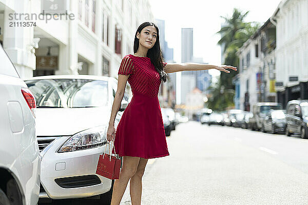 Young woman hailing ride in city street