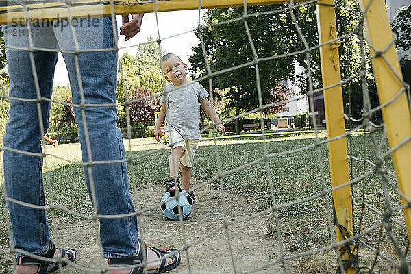 Boy with one leg on soccer ball standing in playground