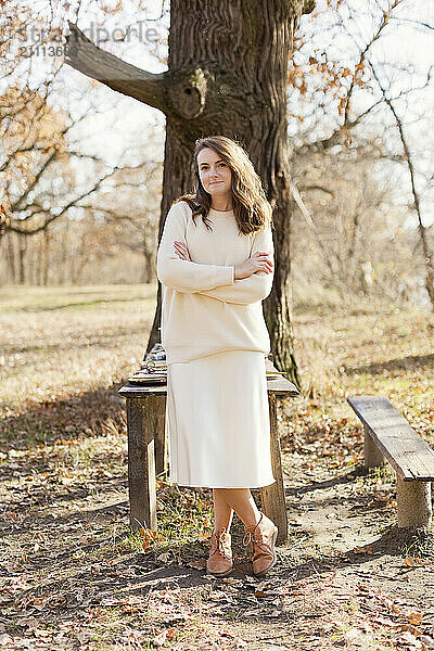 Woman with arms crossed standing near table at forest