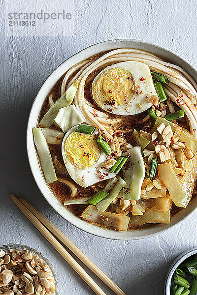 White cabbage soup with miso and udon noodles and boiled eggs and peanuts as topping