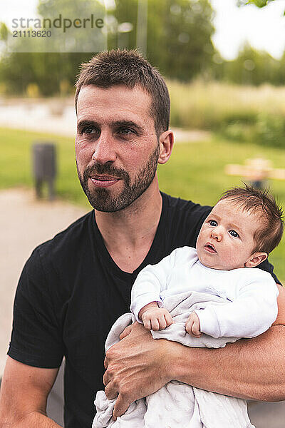 Father carrying baby boy in arm at playground