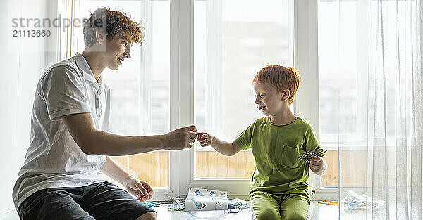 Siblings playing near window at home