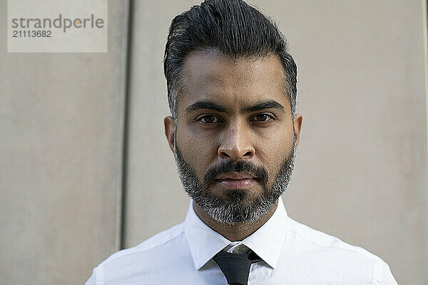 Serious businessman in front of wall