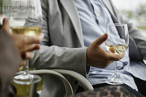 Hands of couple sitting o chair and holding wine glass