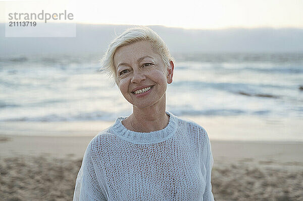 Smiling mature woman with short hair at beach