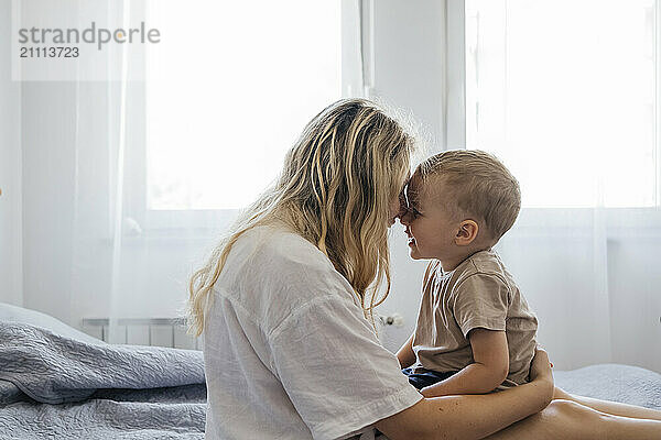 Mother spending leisure time with son on bed at home