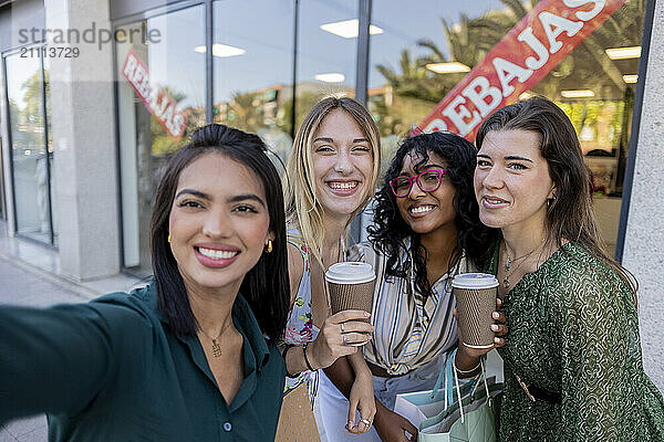 Happy woman taking selfie with friends in street