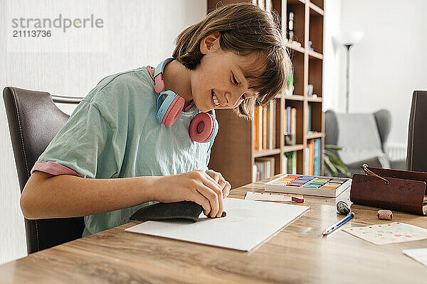 Happy girl sitting near table and drawing at home