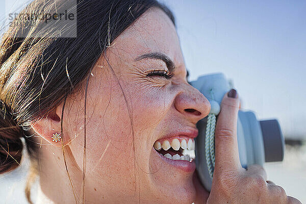 Happy woman photographing with camera on sunny day