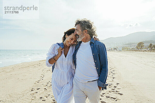 Loving senior couple walking at beach on sunny day