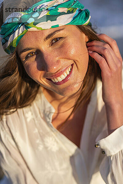 Cheerful woman with hand in hair wearing headscarf