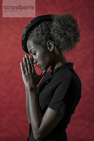 Air stewardess with hands clasped against red background