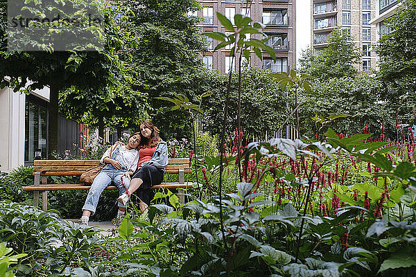 Young gay couple sitting together on bench at park