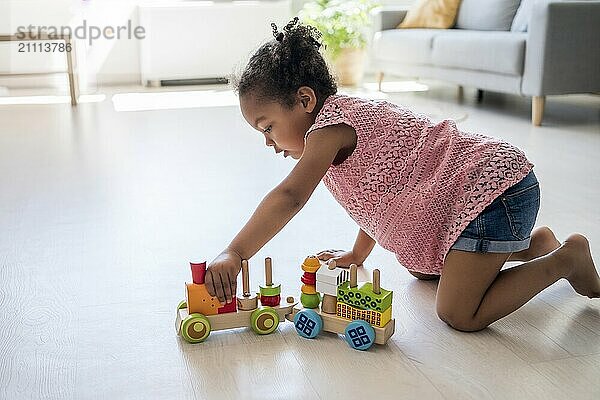 Girl with pigtail playing with toy vehicle at home