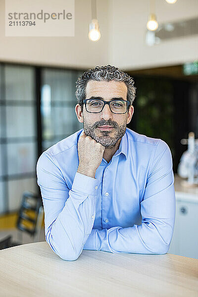 Businessman with hand on chin standing at co working space