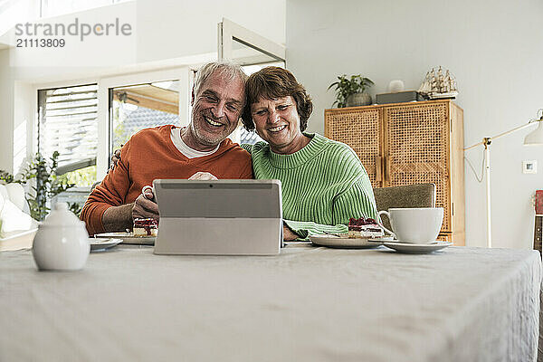 Affectionate couple using digital PC for video call at dining table