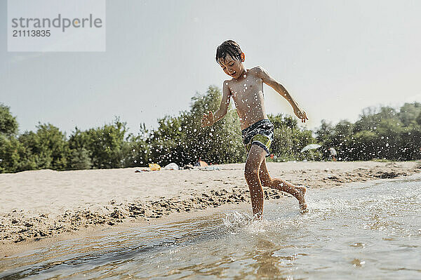 Happy boy running over water on river