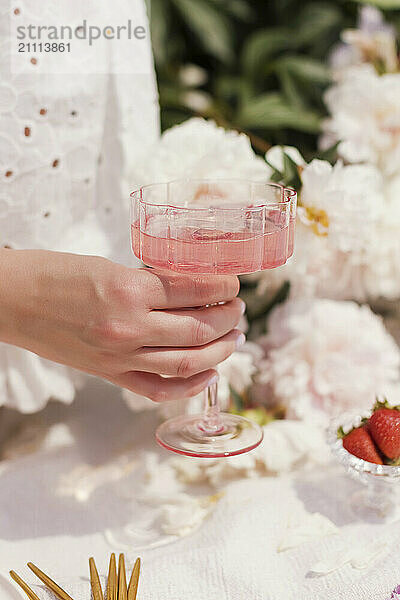 Woman's hand holding glass of pink lemonade