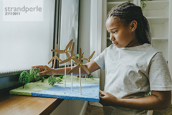 Girl making wind turbines school project on window sill