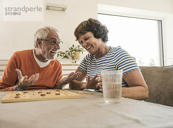 Excited man playing board game with wife at home