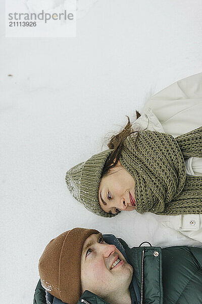 Romantic couple lying down on snow in winter