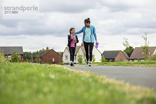 Woman encouraging daughter walking on footpath