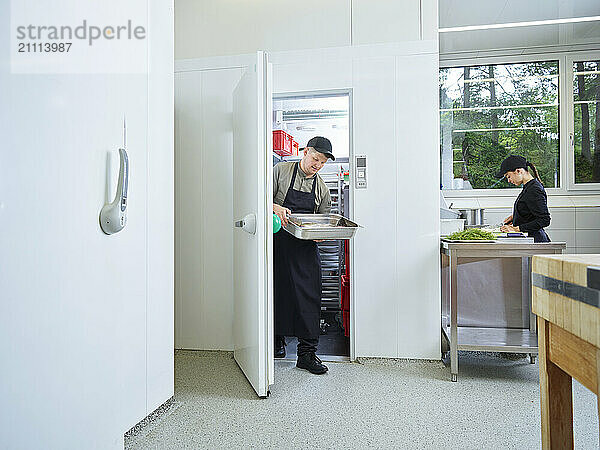 Chef removing frozen fish from cold storage in restaurant