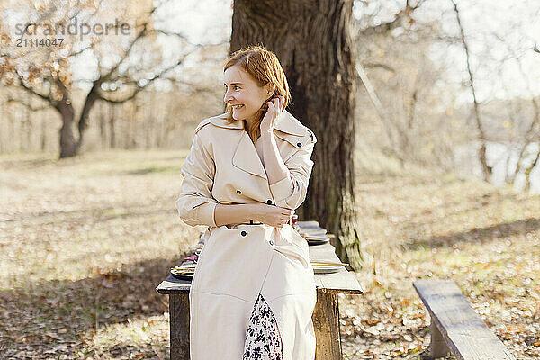 Smiling woman leaning on table in forest