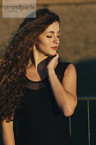 Beautiful woman with eyes closed standing in sunlight during summer