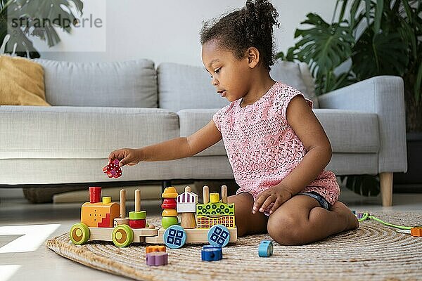 Girl playing toy vehicle near sofa at home