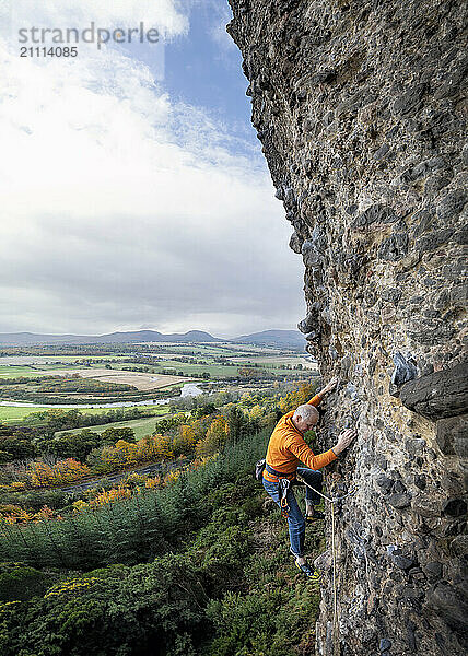 Mature man climbing on Moy Rock in Scotland